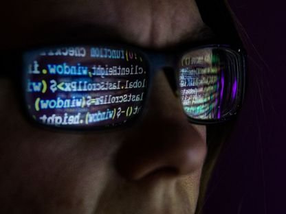 شخص يجلس أمام شاشة حاسوب وينعكس في زجاج عدسات نظارته كود برمجي - Bloomberg - Bloomberg